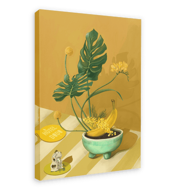 The Ikebana Banana Giclée Canvas Print by Hôtel Dodo showcases tropical foliage, yellow flowers, bananas in a bowl, a figurine, and a key tag labeled "Hôtel Dodo," all arranged on a striped surface set against a mustard-yellow background.