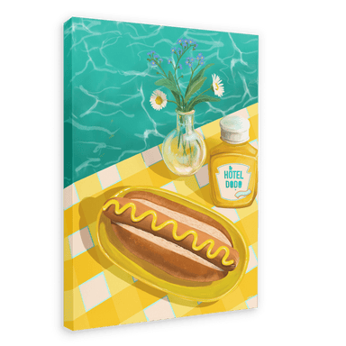 A giclée canvas print named "Poolside Hotdog" by the brand Hôtel Dodo features an illustration of a hotdog with mustard on a yellow checkered tablecloth, accompanied by a vase of flowers and a bottle of Hôtel Dodo mustard. The scene is set against a backdrop of tropical foliage and a sparkling pool.