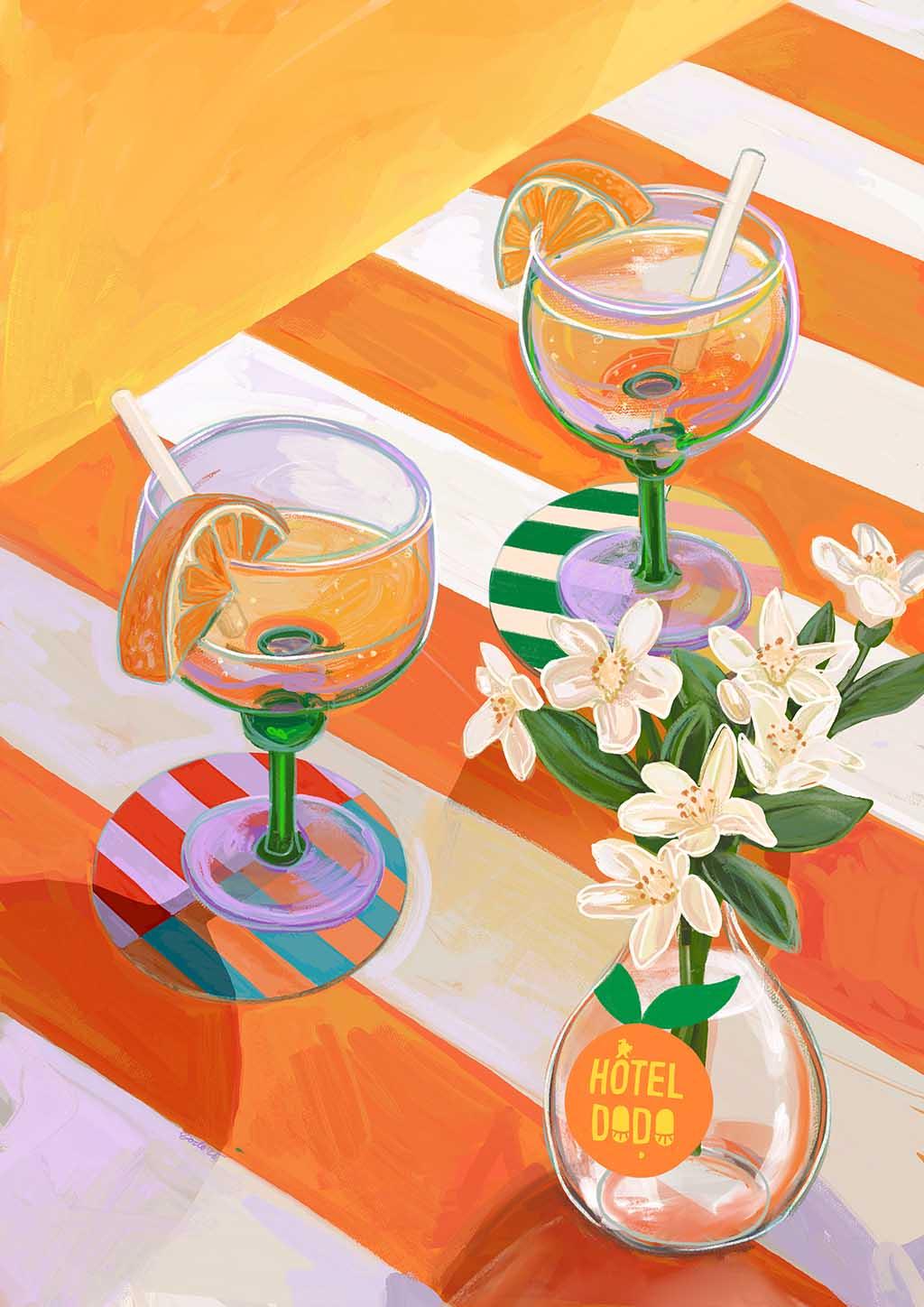 Two margarita glasses with orange slices and straws rest on a striped table beside a vase of white flowers, styled next to the Hôtel Dodo "A L'Orange Giclée Art Print.