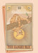 The Hanged Man Art Print by Tarot Cats features an orange cat hanging upside down from a tree branch, set against a backdrop of a sun and abstract patterns.