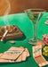 The Lucky Ducky Casino Giclée Art Print by Hôtel Dodo features a green casino table with poker chips, playing cards, a martini glass with an olive, a smoldering cigarette in an ashtray, and an open matchbook.