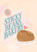 Matte art print titled “Sticky Beans Bakery Loaf Of Your Life” by International Pestsellers features a sign with the bakery name, Hotel Dodo logo, heart, and bread loaf. Below: “Find the loaf of your life!”.