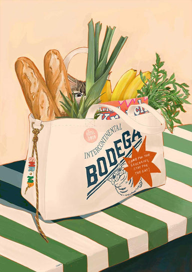 The Bodega Bounty Giclée Art Print by Hôtel Dodo features a white "Bodega" bag on a striped table, filled with baguettes, bananas, leeks, carrots, canned food—and a curious cat—bringing bodega vibes to your space.